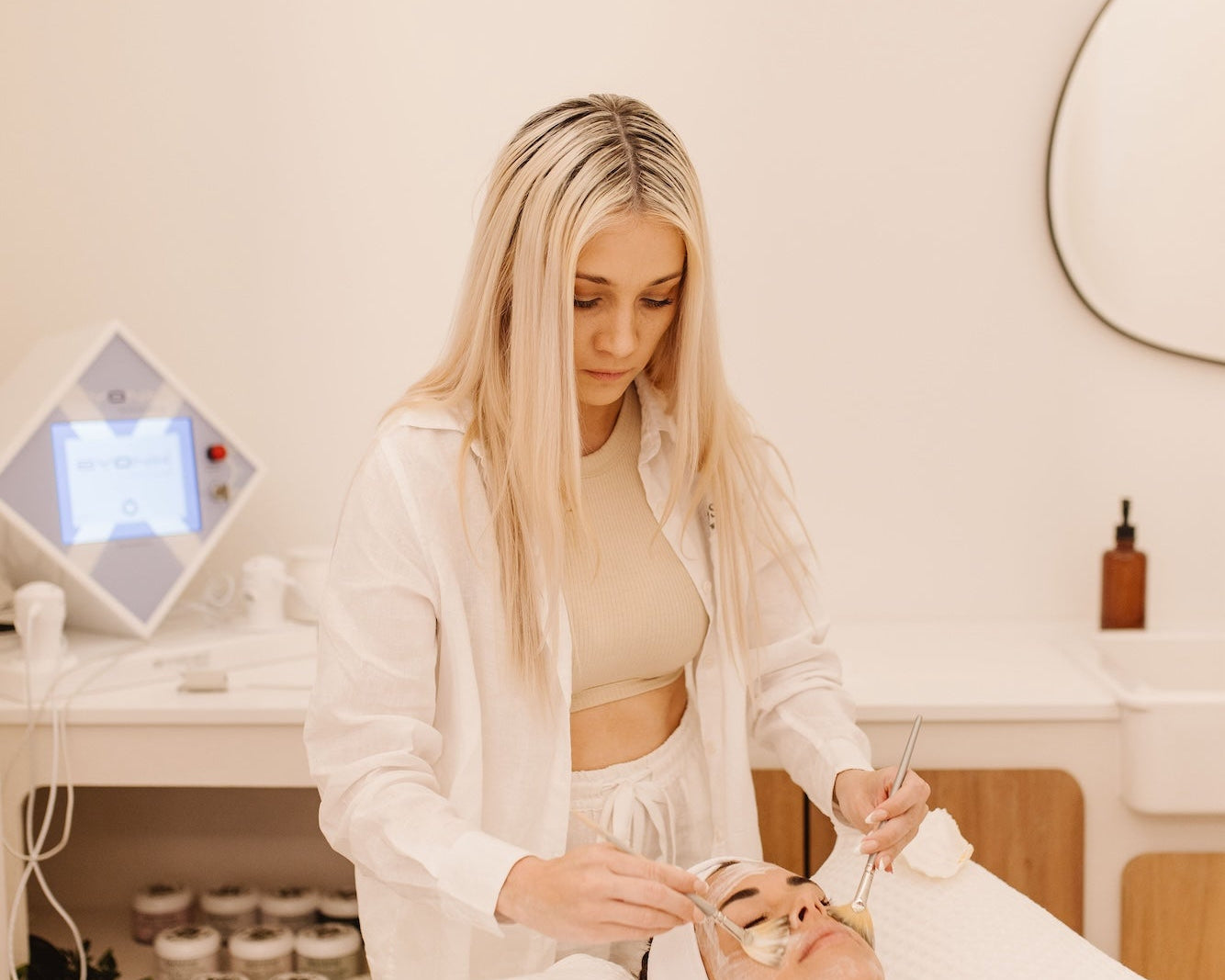 Wellness practitioner performing a facial treatment on a client at a spa.