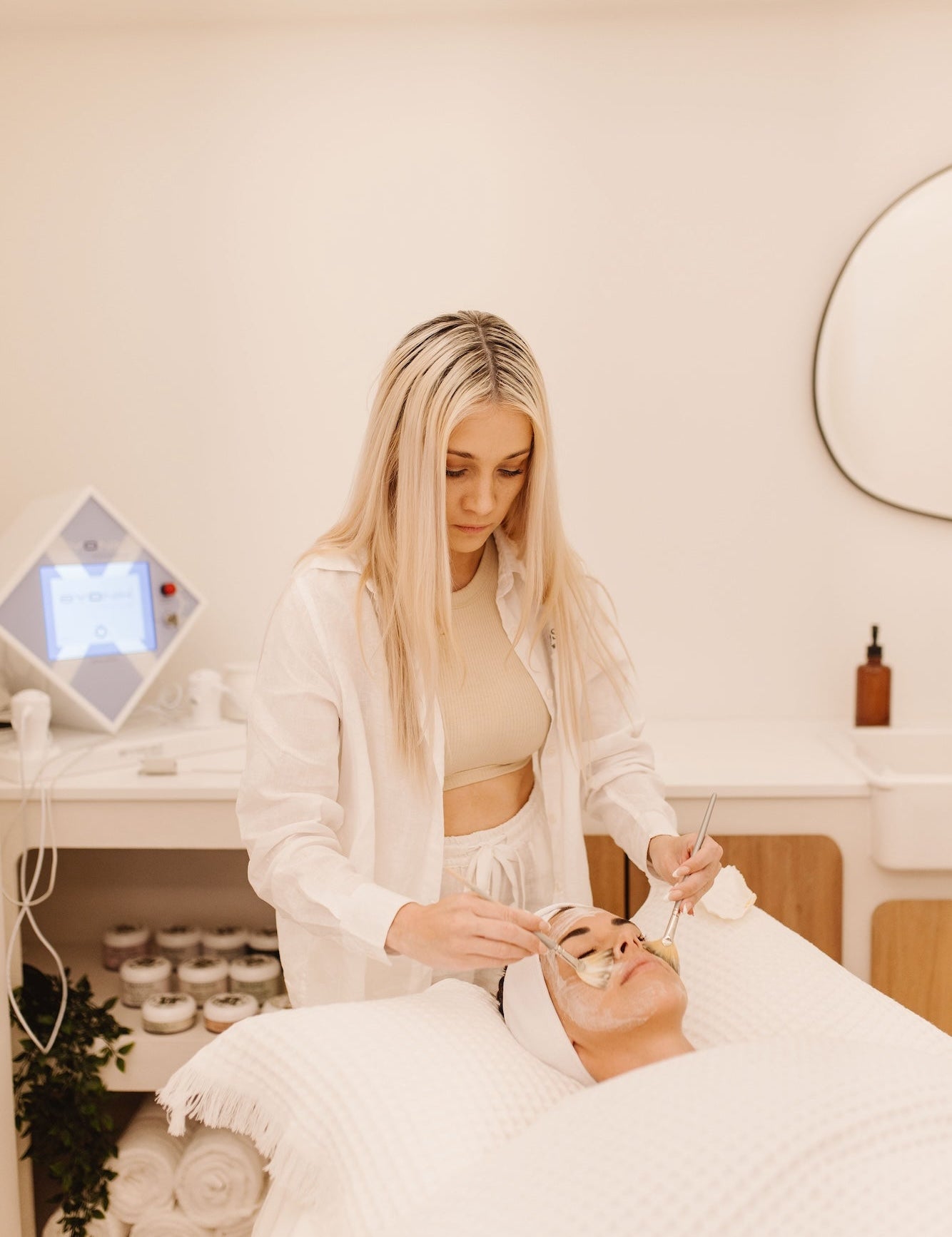 Wellness practitioner performing a facial treatment on a client at a spa.