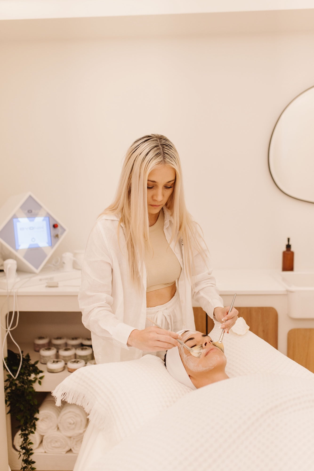 Wellness practitioner performing a facial treatment on a client at a spa.