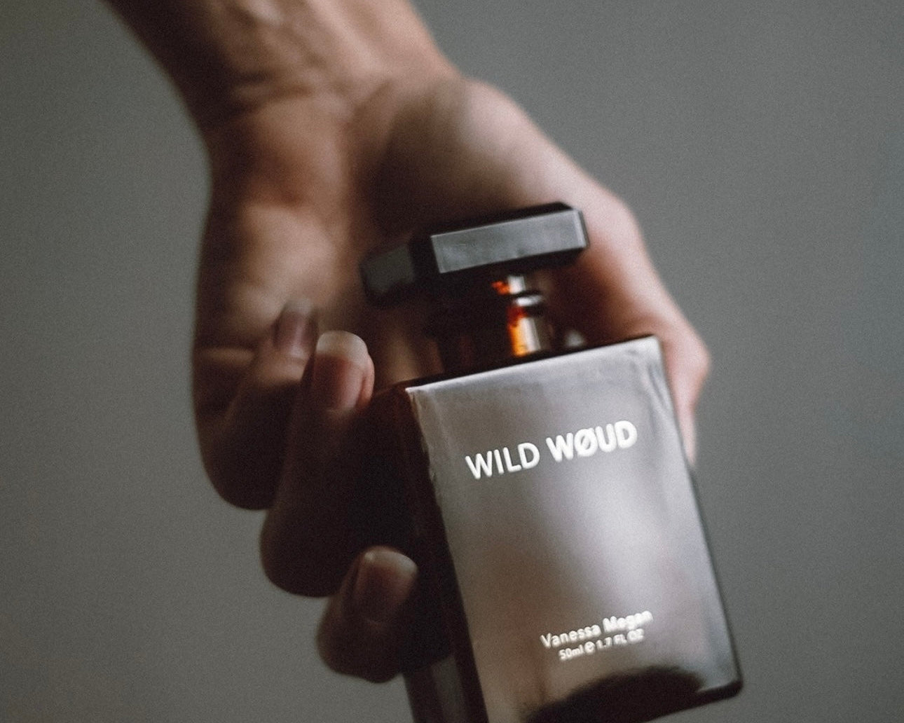 Hand holding a bottle of Vanessa Megan Wild Woud natural perfume.