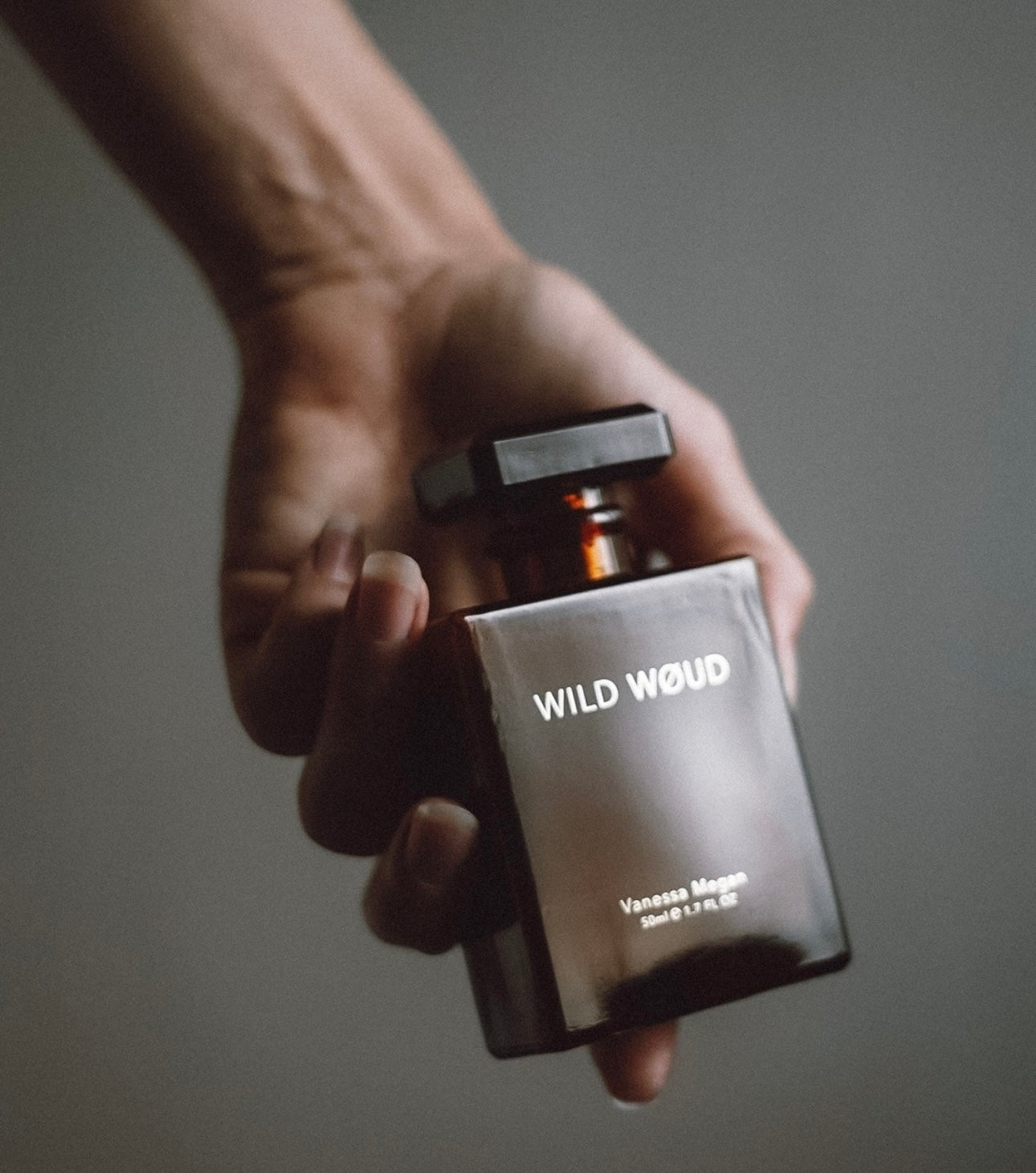 Hand holding a bottle of Vanessa Megan Wild Woud natural perfume.