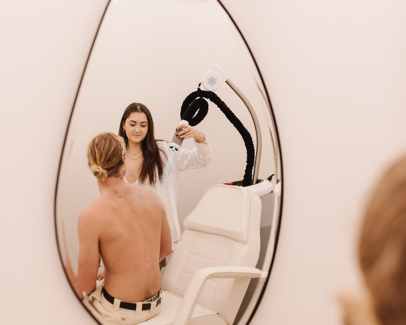 Wellness practitioner applying localised cryotherapy to a client’s upper back.