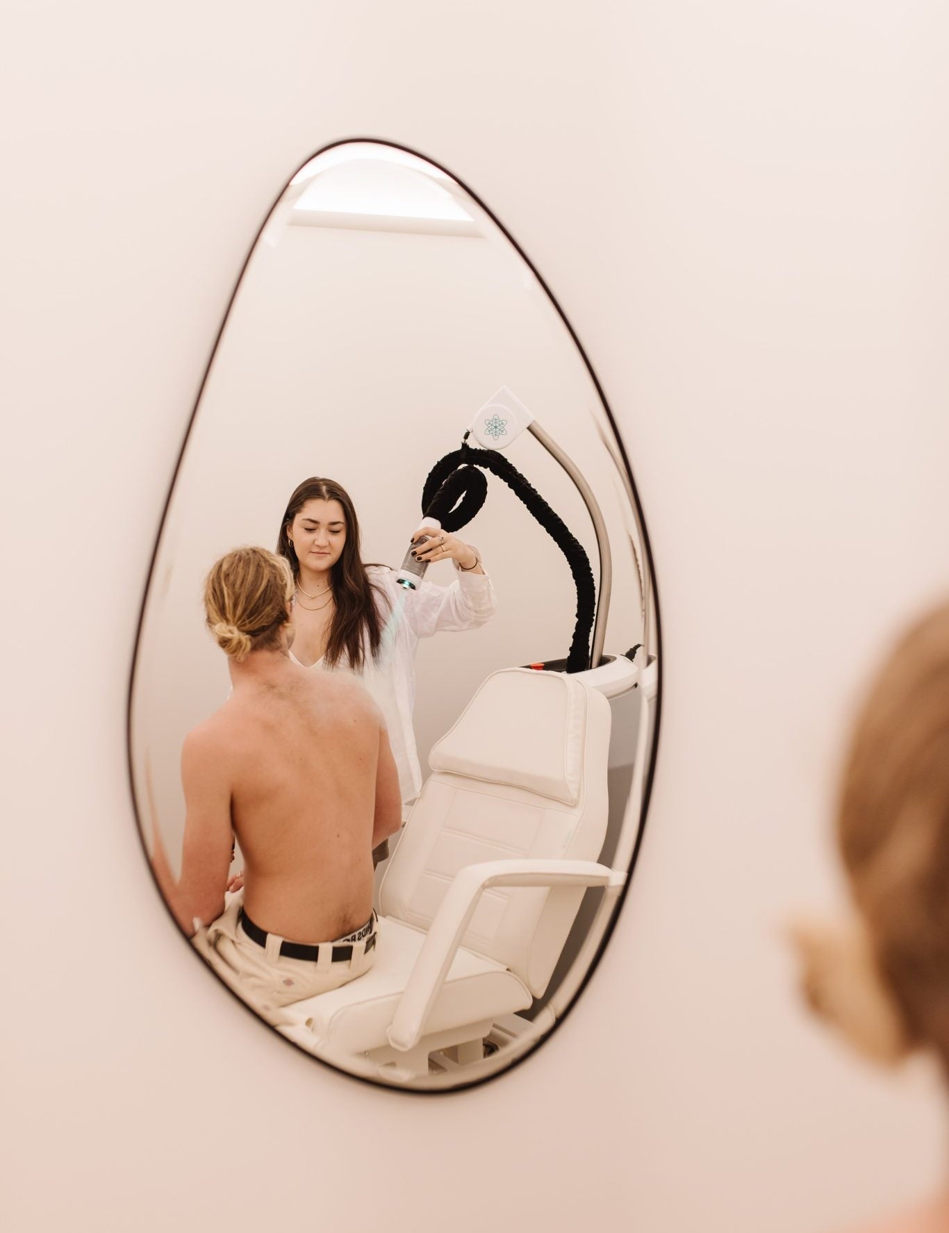 Wellness practitioner applying localised cryotherapy to a client’s upper back.