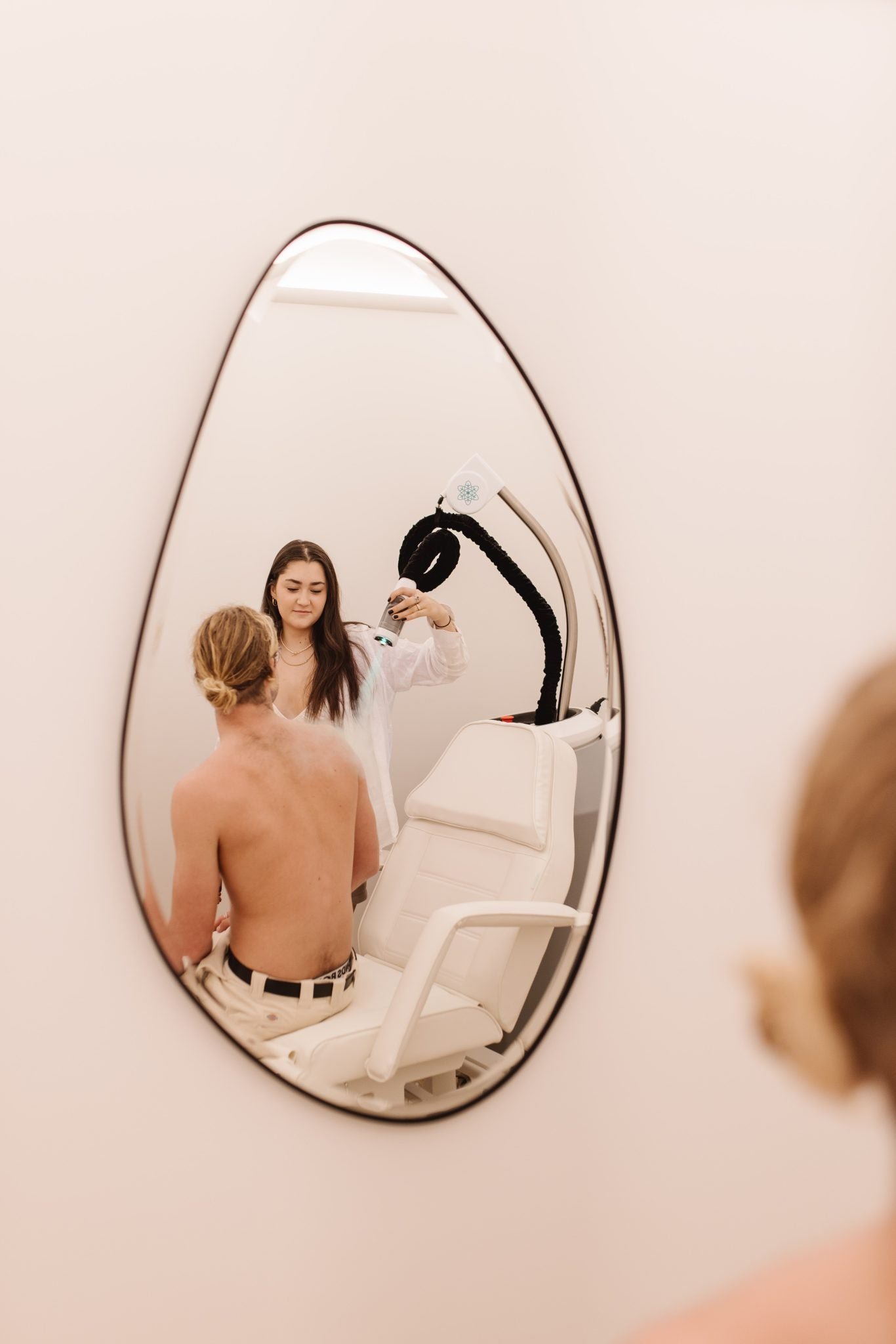 Wellness practitioner applying localised cryotherapy to a client’s upper back.